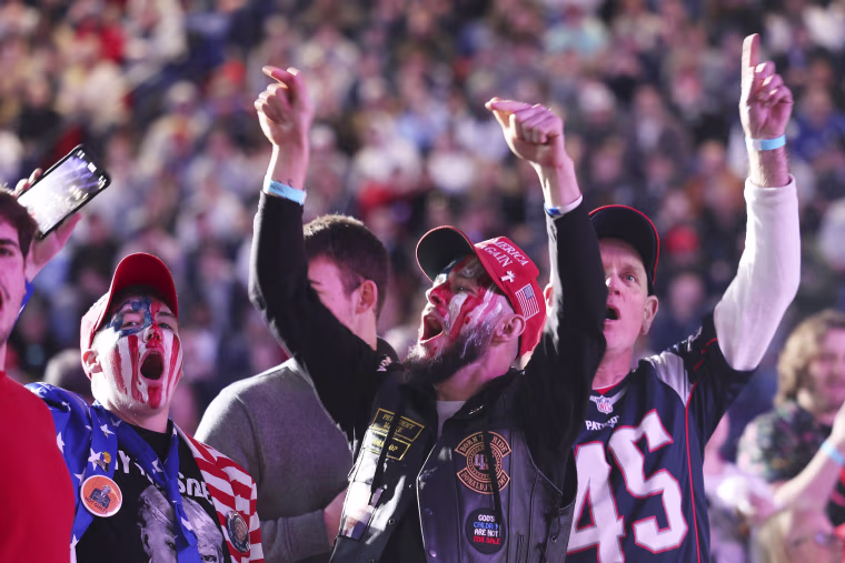 Two people with American flag-painted faces cheer during a rally for former President Donald Trump.