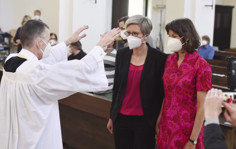 Vicar Wolfgang Rothe blesses Christine Walter, center, and Almut Muenster in St Benedict's Church in Munich, on May 9, 2021.