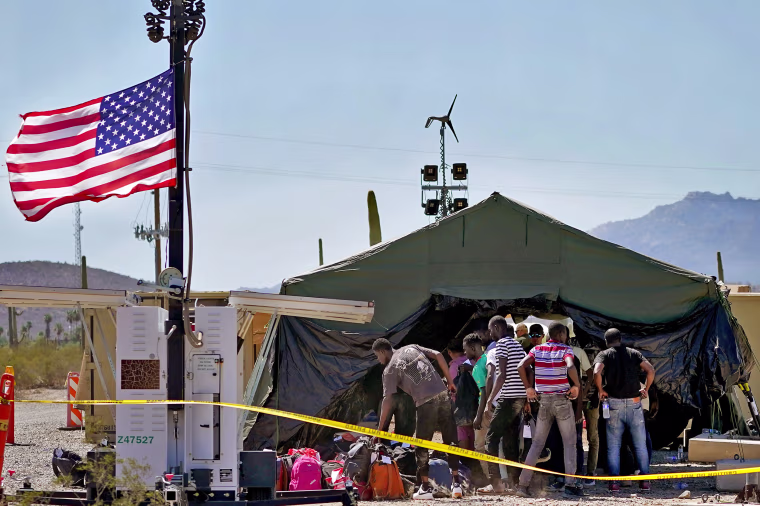 A group of men detained by U.S. Customs and Border Patrol after crossing the border wall in the Tucson Sector of the U.S.-Mexico border are processed at a makeshift intake center on Aug. 29, 2023.