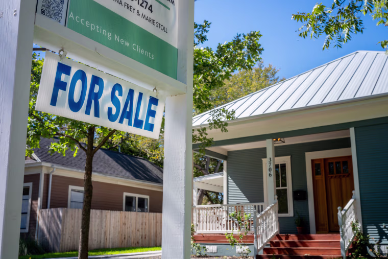 A "for sale" sign sits in front of a home.