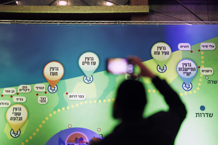 An attendee takes a picture near a map suggesting a vision for Israeli settlements in Gaza at the conference in Jerusalem on Sunday.