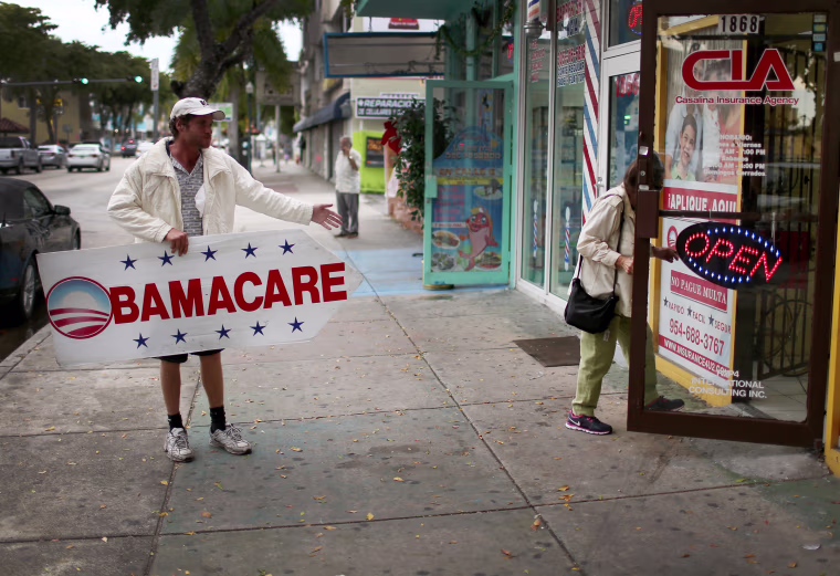 Man holding "Obamacare" sign.