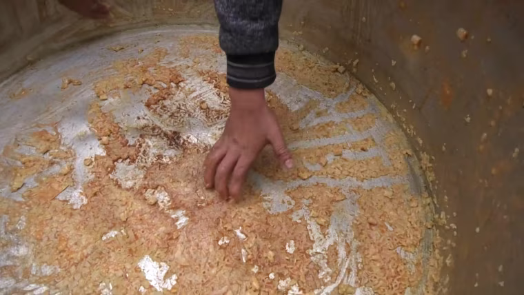 Child scrapes pot for food in Gaza.