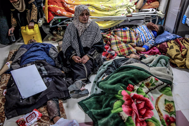 Image: A woman sits among Palestinians at Al-Shifa hospital in Gaza City