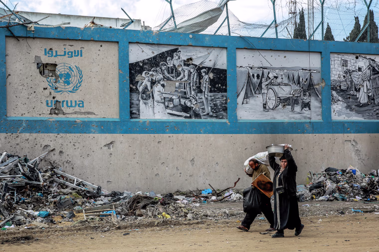 People walk past the damaged Gaza City headquarters of the United Nations Relief and Works Agency on Feb. 15, 2024.