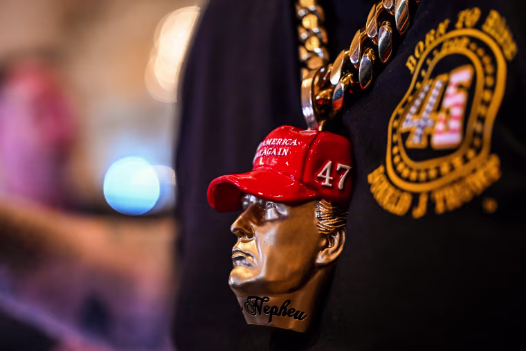 A supporter of Donald Trump wears a Trump bust jewelry.