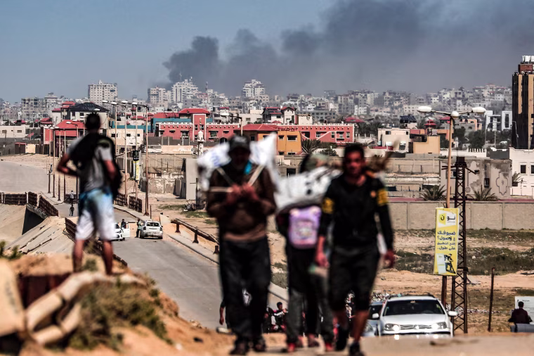 Image: Smoke rises above buildings during Israeli bombardment as people fleeing the Al-Shifa hospital