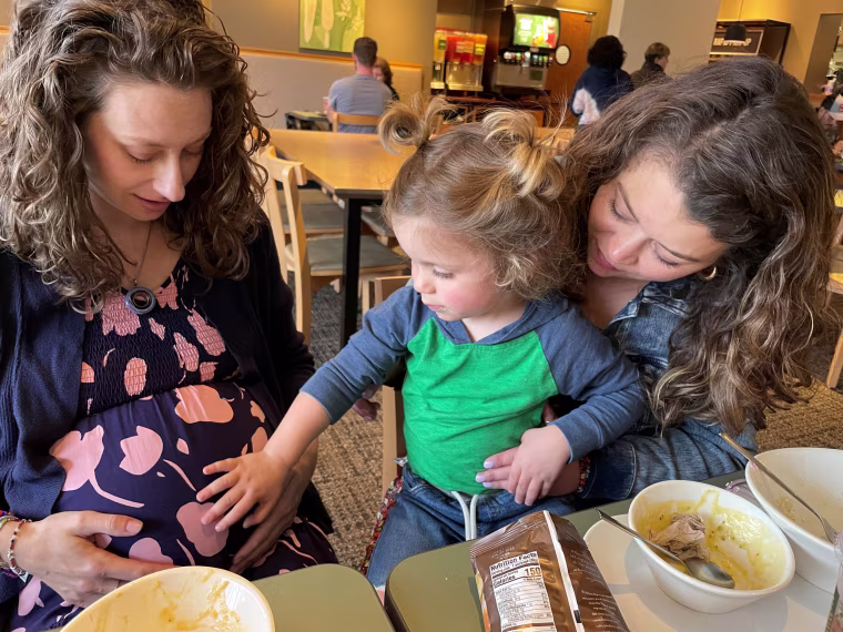 Alex Kamer's older son touches the pregnant belly of Zientek, who served as the surrogate for the new baby.