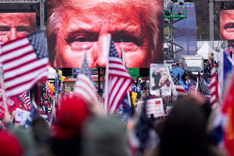 An image of President Donald Trump appears on video screens