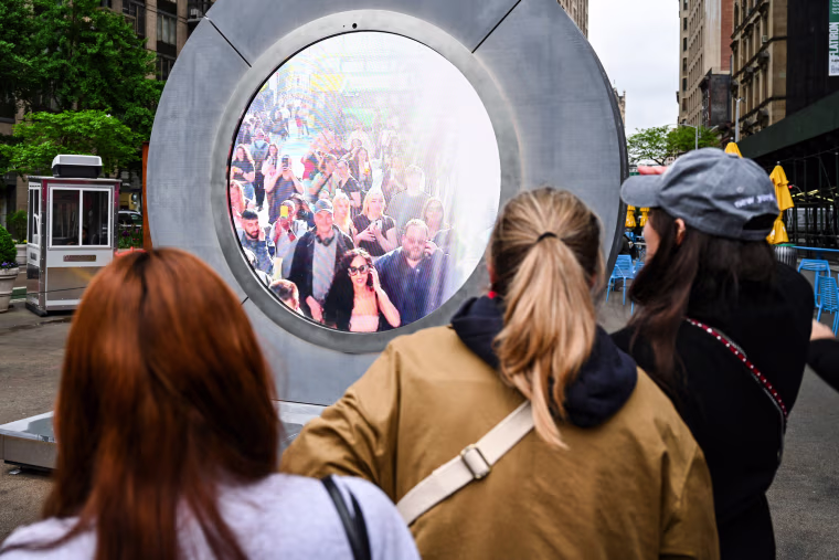 People interact with a massive circular livestream video "portal"