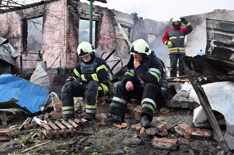 Ukrainian firefighters rest after battling a fire at a house destroyed by a Russian drone attack in Kharkiv on May 21, 2024.