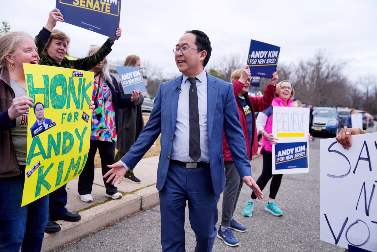Supporters hold signs for Andy Kim as he greets them