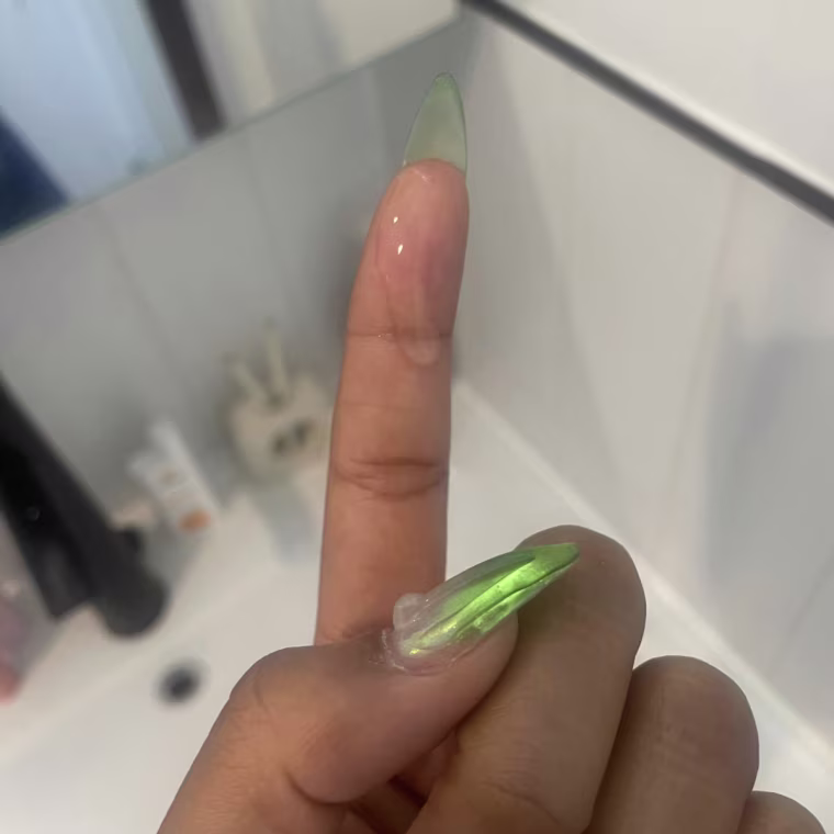 Close-up of a drop of CosRx Hyaluronic Acid Hydra Power Essence shown on a finger in front of a sink.