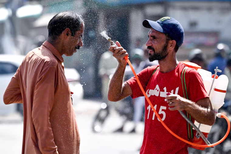 A volunteer sprays water on a bypasser's face 