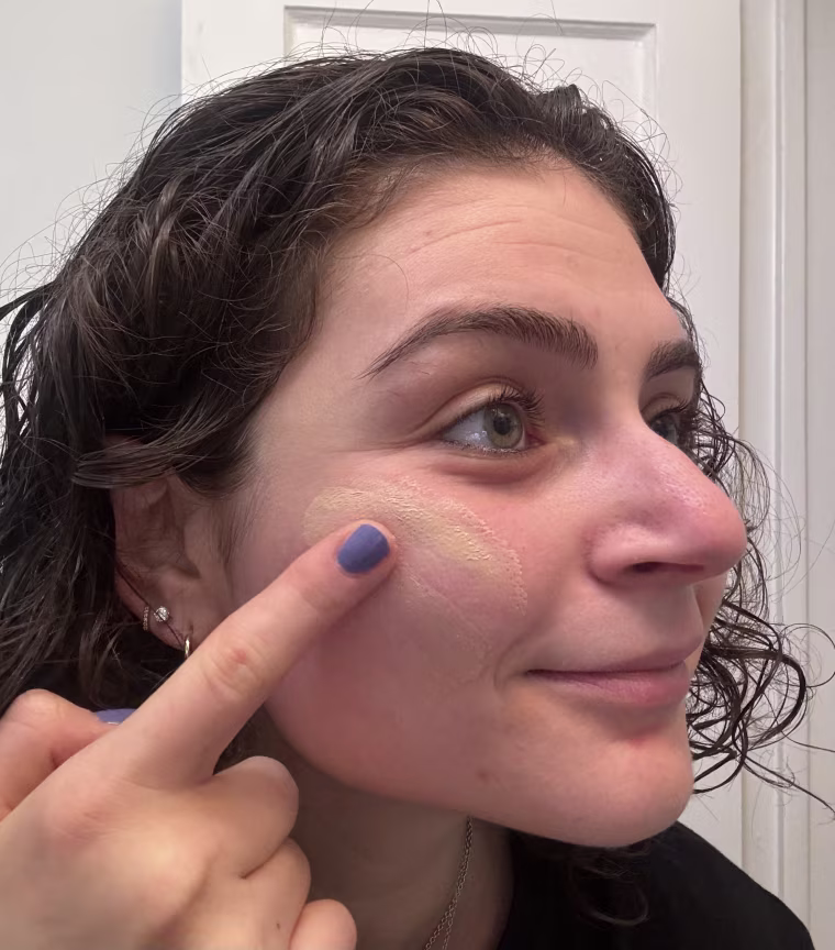 A woman applying Tower 28’s SunnyDays SPF 30 Tinted Sunscreen.