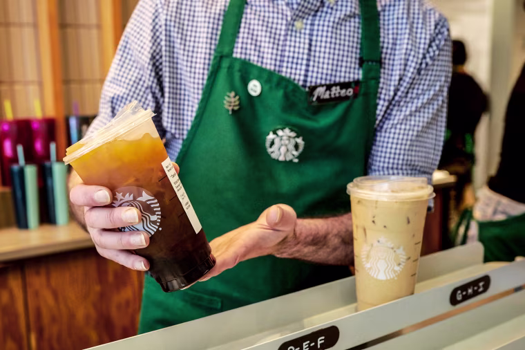 A barista places an iced coffee in the mobile pickup area 