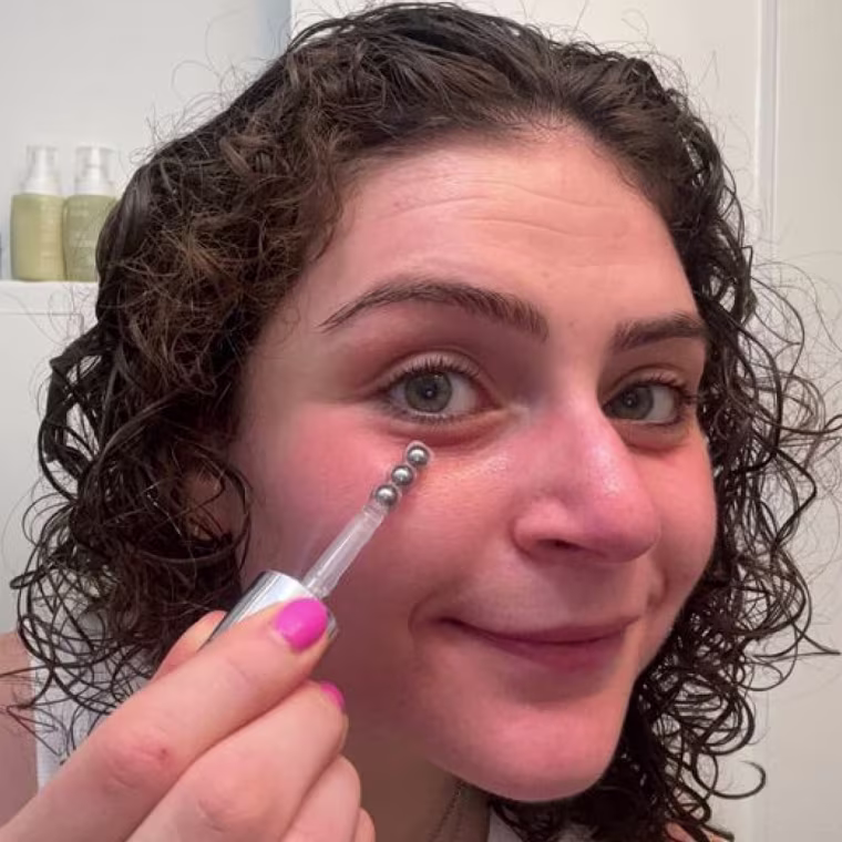 Woman applying eye cream applicator to her under eyes