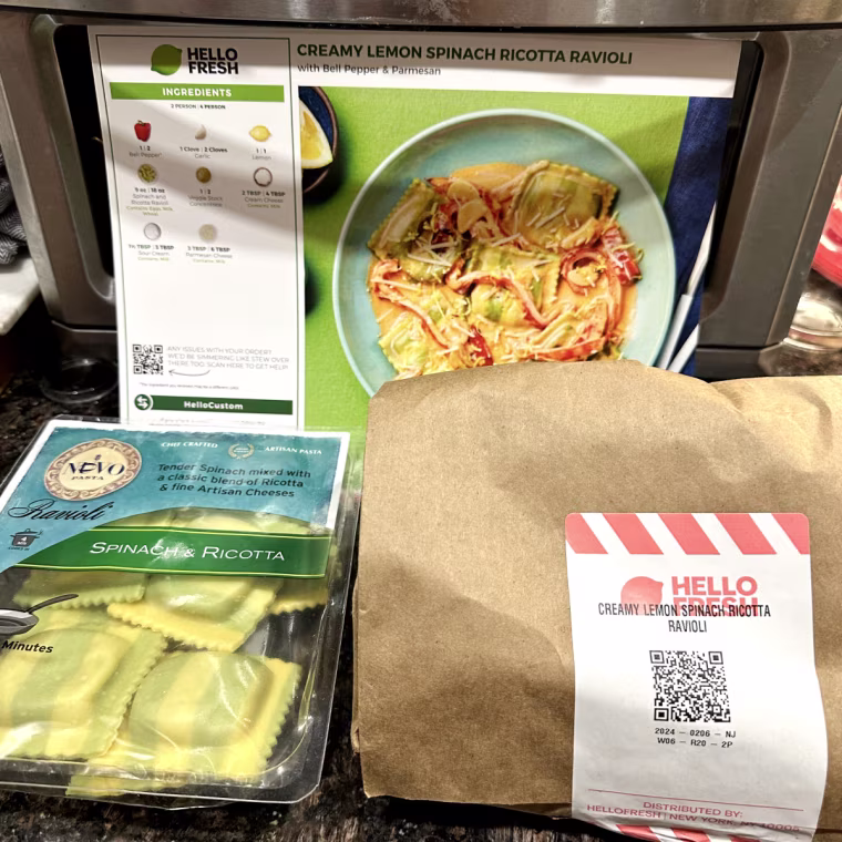 Paper bag, HelloFresh recipe card and package of ravioli on a dark brown countertop and resting on air fryer