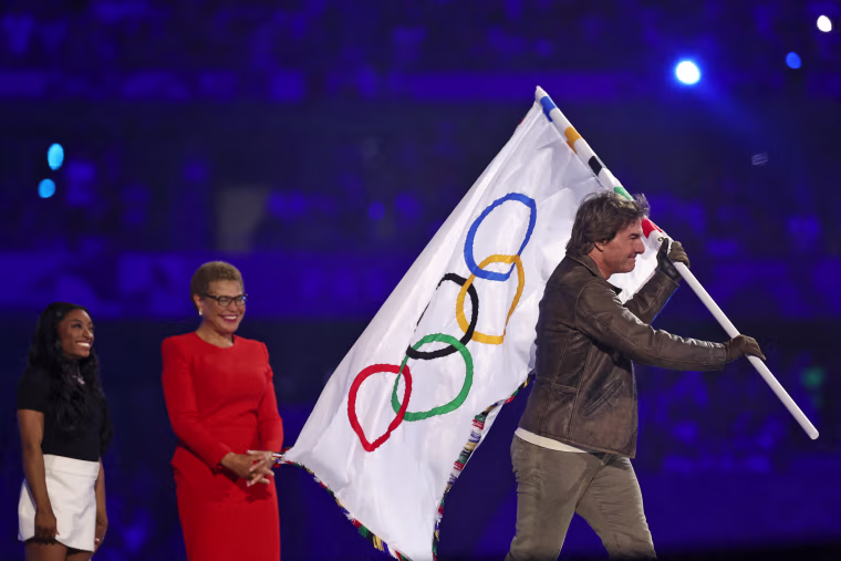 Tom Cruise holds the Olympic flag in front of Los Angeles Mayor Karen Bass as the flag is transferred to the next host city at the closing ceremony of the Paris 2024 Olympic Games.