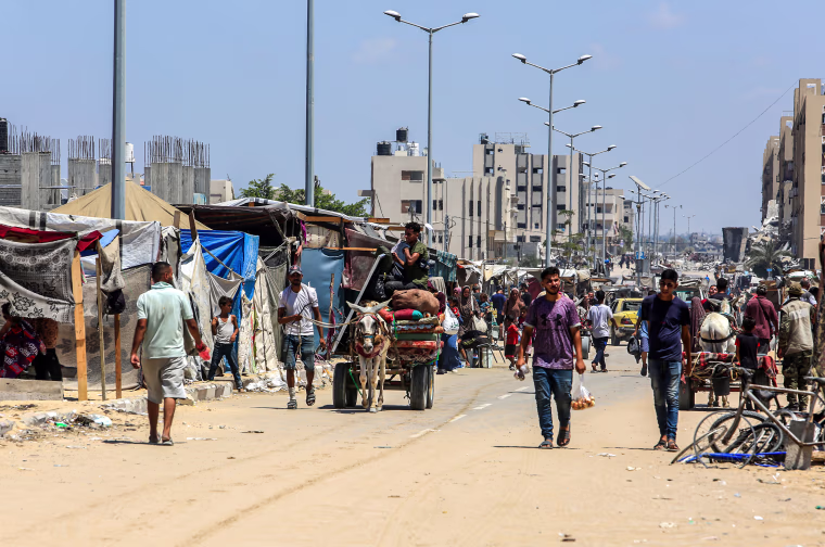 Palestinians, living in makeshift tents, leave to find safer areas as they carry their belongings.