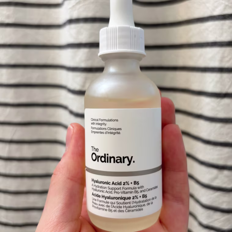 Woman holding serum bottle and taking out dropper