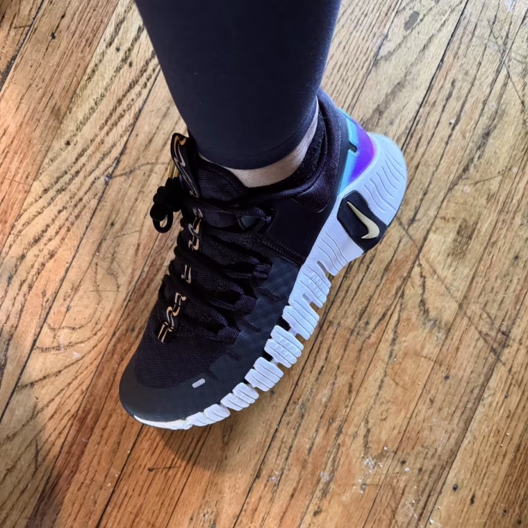 A woman’s foot wearing a black Nike Metcon training shoe.