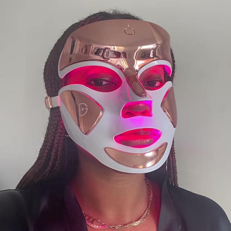 A close up of Morris wearing the Dennis Gross DRx Spectralite Faceware Pro face mask. The lights emit a soft glow from the eye, nose, and mouth cutouts.