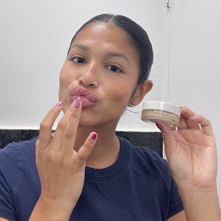 Woman applies Naturium’s Phyto-Glow Lip Mask directly onto her lips using her fingers in the bathroom.