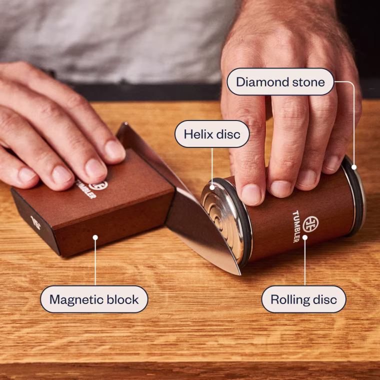To use the Tumbler Knife Sharpener, you hold the magnetic block in place with one hand and move the rolling disc back and forth along the blade with the other.