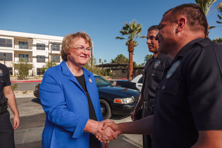 Photo of subject Lisa Middleton in a blue suit shaking hands with a police officer 