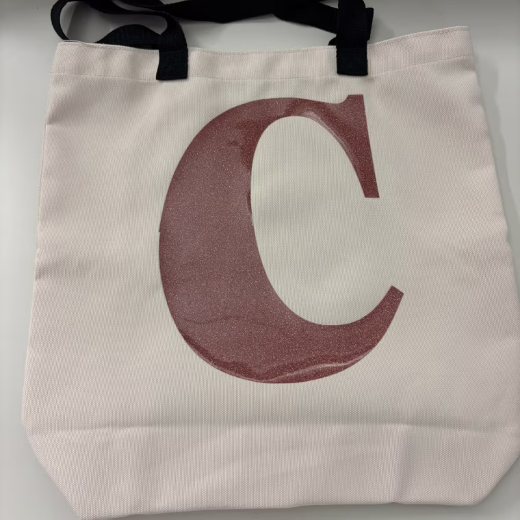 A monogrammed tote bag made with the Cricut Joy Xtra lays flat on a counter.