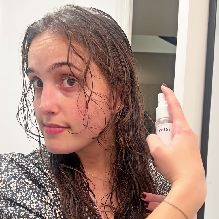 Woman applies Ouai Leave-In Conditioner to her brown, fine, wavy, damp hair