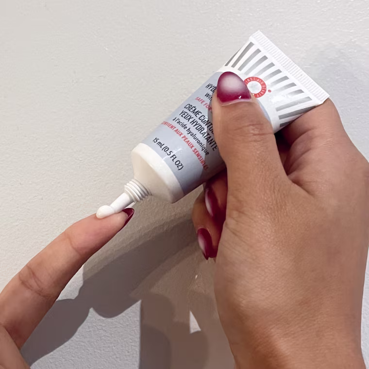 Woman dispenses a pea-sized amount of First Aid Beauty’s Hydrating Eye Cream on her finger.