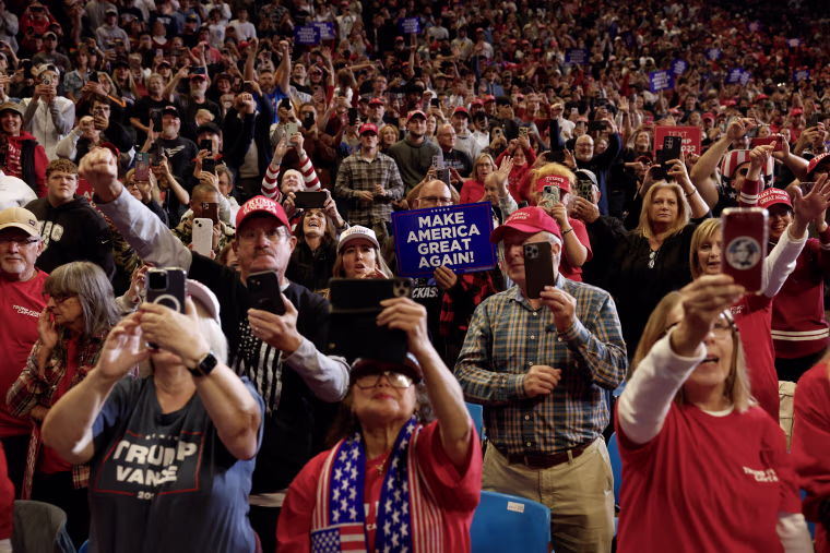 Trump supporters hold signs and phones.