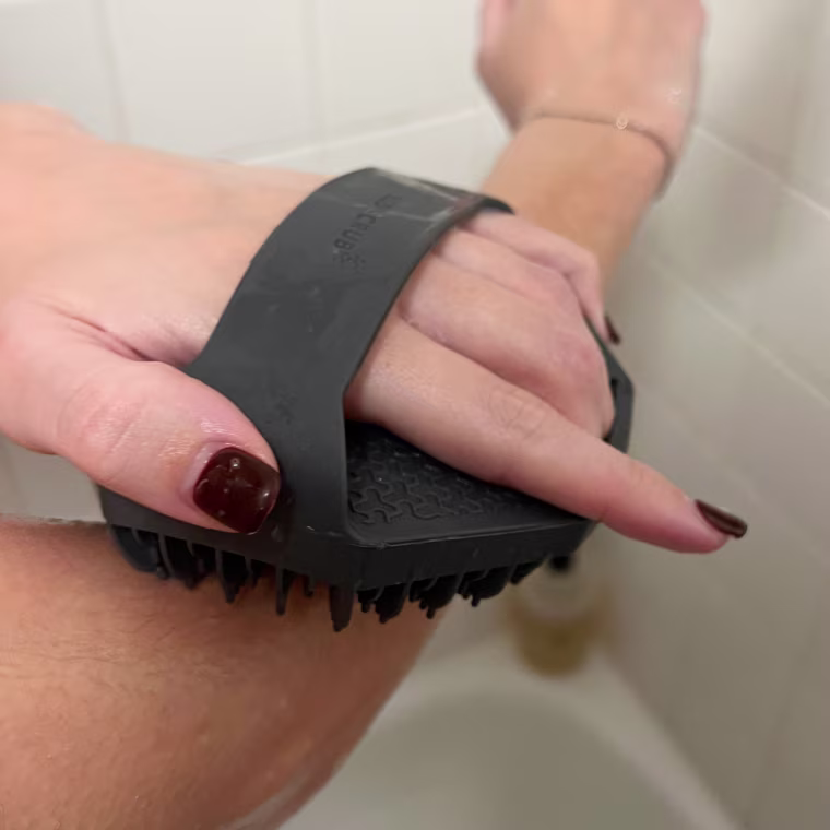 Woman scrubbing arm using gray silicone scrubber
