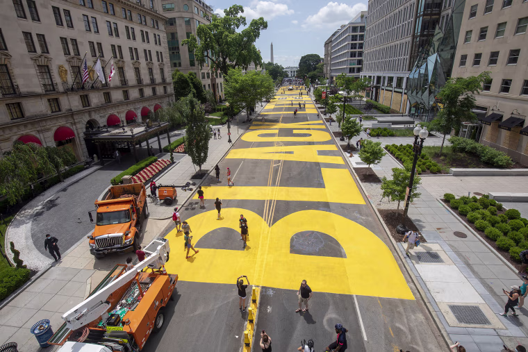 People walk down 16th street after volunteers, with permission from the city, painted "Black Lives Matter" on the street near the White House