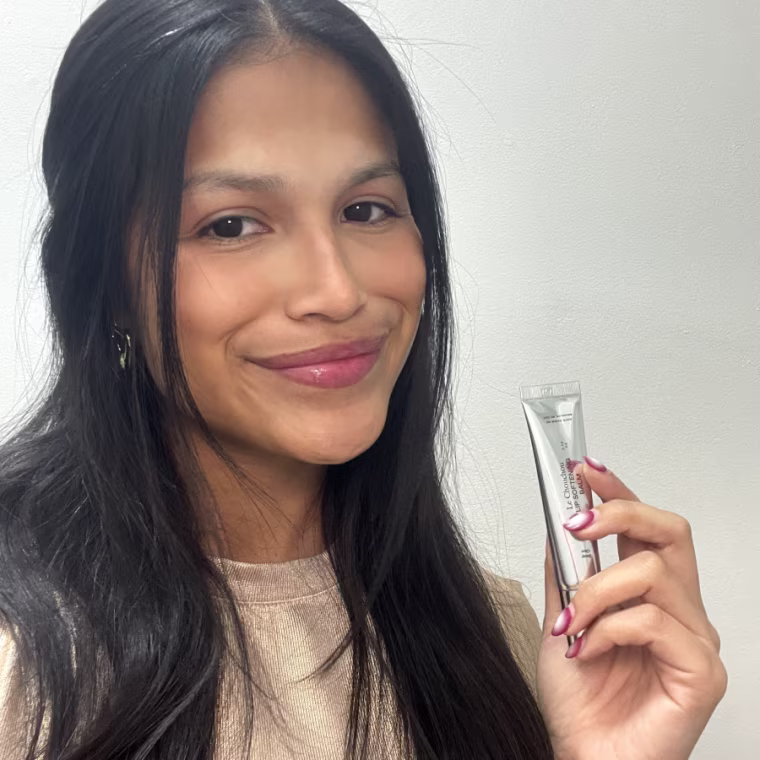 Smiling woman holding metallic lip balm tube