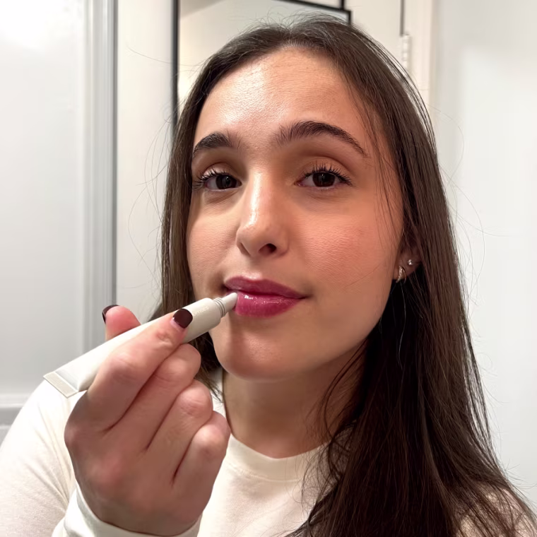 Woman in bathroom applying sheer lip balm