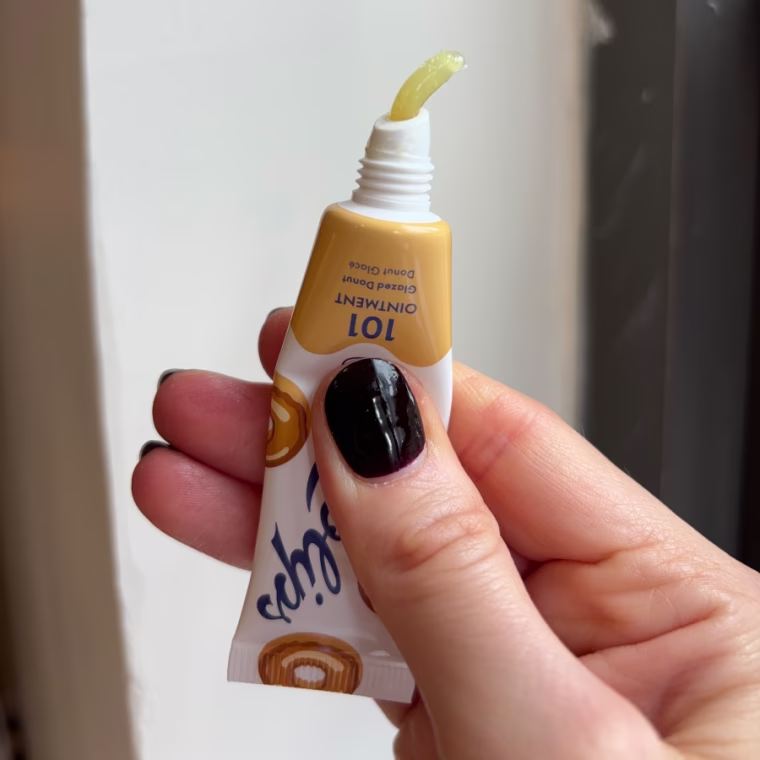Woman’s hand squeezing out lip balm from tube