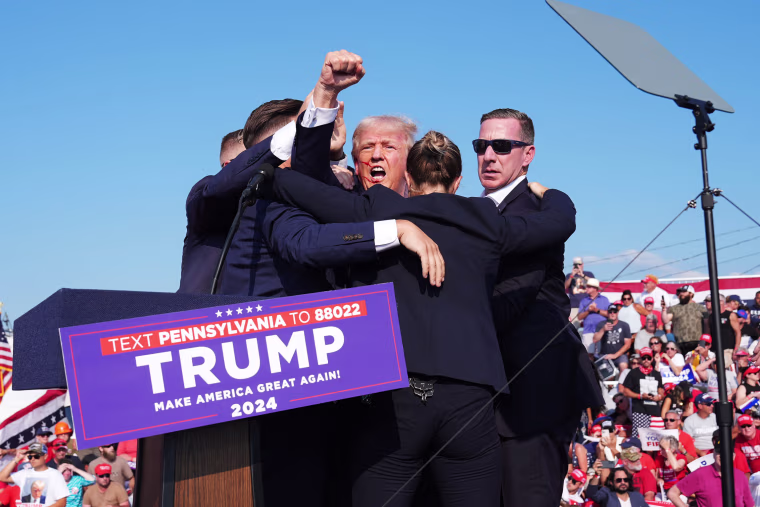 Donald Trump raises his arm with blood on his face