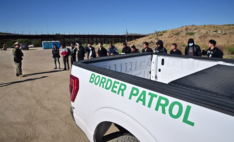 A large group of Chinese migrants, including three from Bangladesh, line up for a Customs and Border Patrol officer