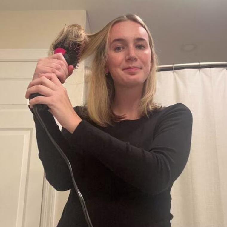 Woman dries and brushes her hair simultaneously using the Revlon One Step Volumizer Plus.