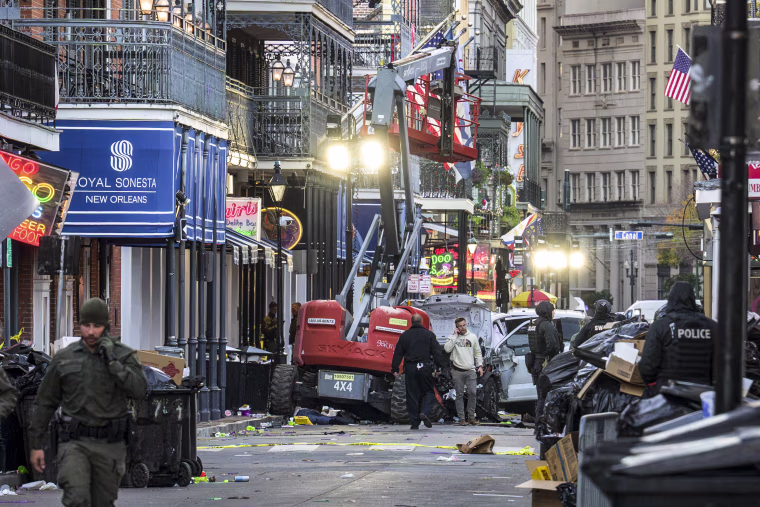 Image: Police investigators surround a white truck that has been crashed into a work lift