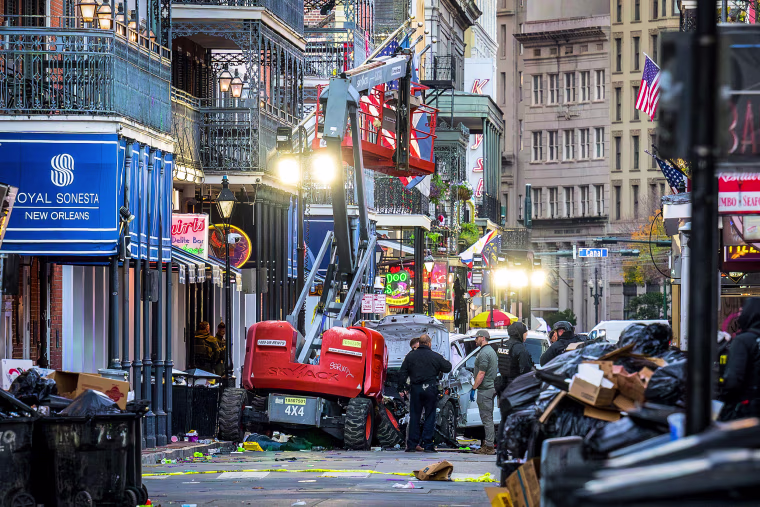 Image: Police investigators surround a white truck that has been crashed into a work lift