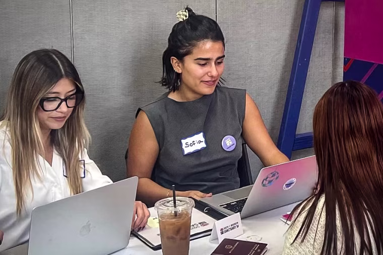 A volunteer and translator help an asylum applicant with her forms
