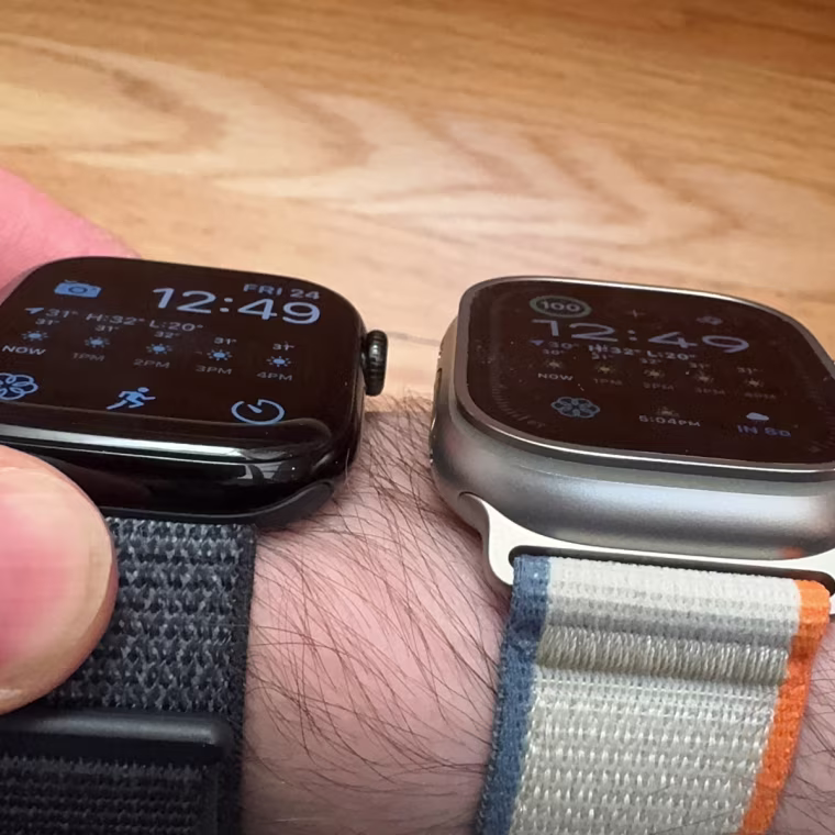 A close up image of the Apple Watch Series 10 and Apple Watch Ultra 2 on the author’s wrist, taken from an off-angle. The Apple Watch Series 10 looks brighter than the Apple Watch Ultra 2.