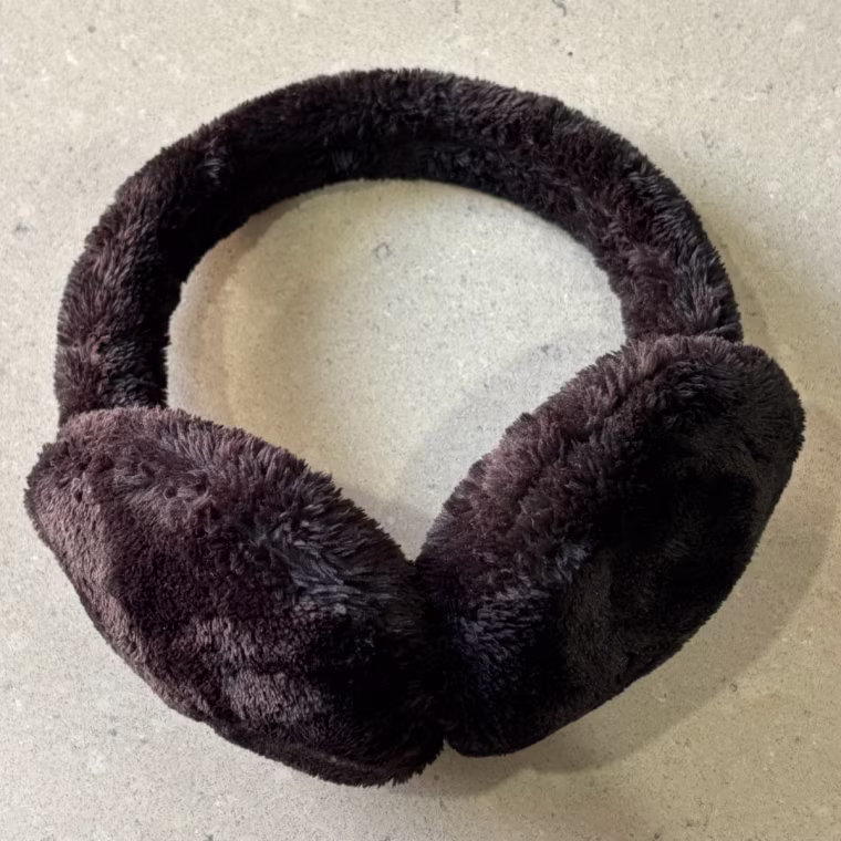 Black fuzzy earmuffs from Muji lying on a table.
