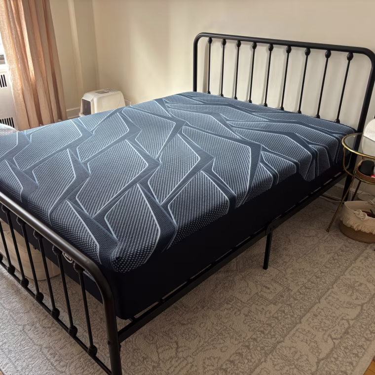 The Serta iSeries Hybrid 2.0 Mattress on a black bed frame in a bedroom.