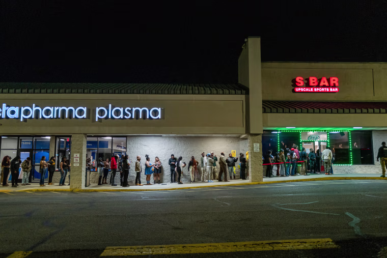 A line of people wait outside of S Bar