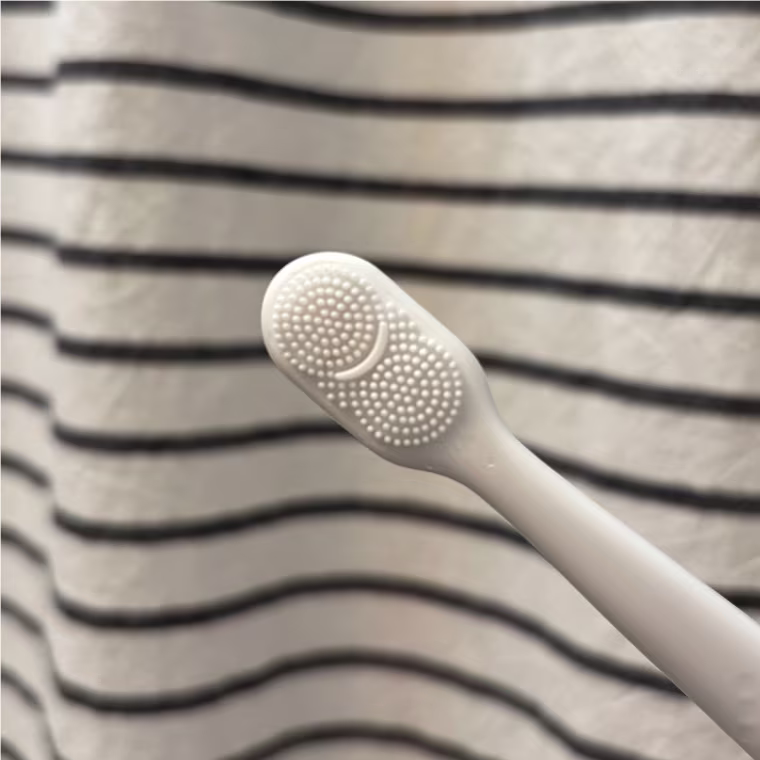 A close-up image of the white silicone tongue and cheek scraper that’s built into the back of the Colgate Total Active Prevention Foaming Clean Toothbrush.